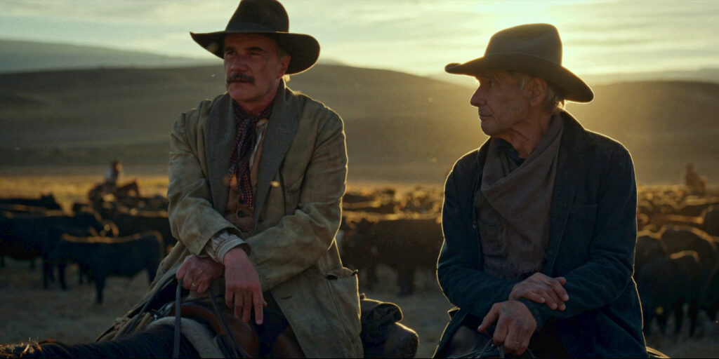 Tim DeKay and Harrison Ford in a scene from episode one of 1923. Both are sitting on horseback with the setting sun and a herd of cattle in the background.