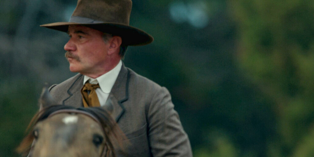 Tim DeKay as Bob Strafford in season 1 episode 3 of 1923. Bob is dressed in period clothes and is riding a horse.